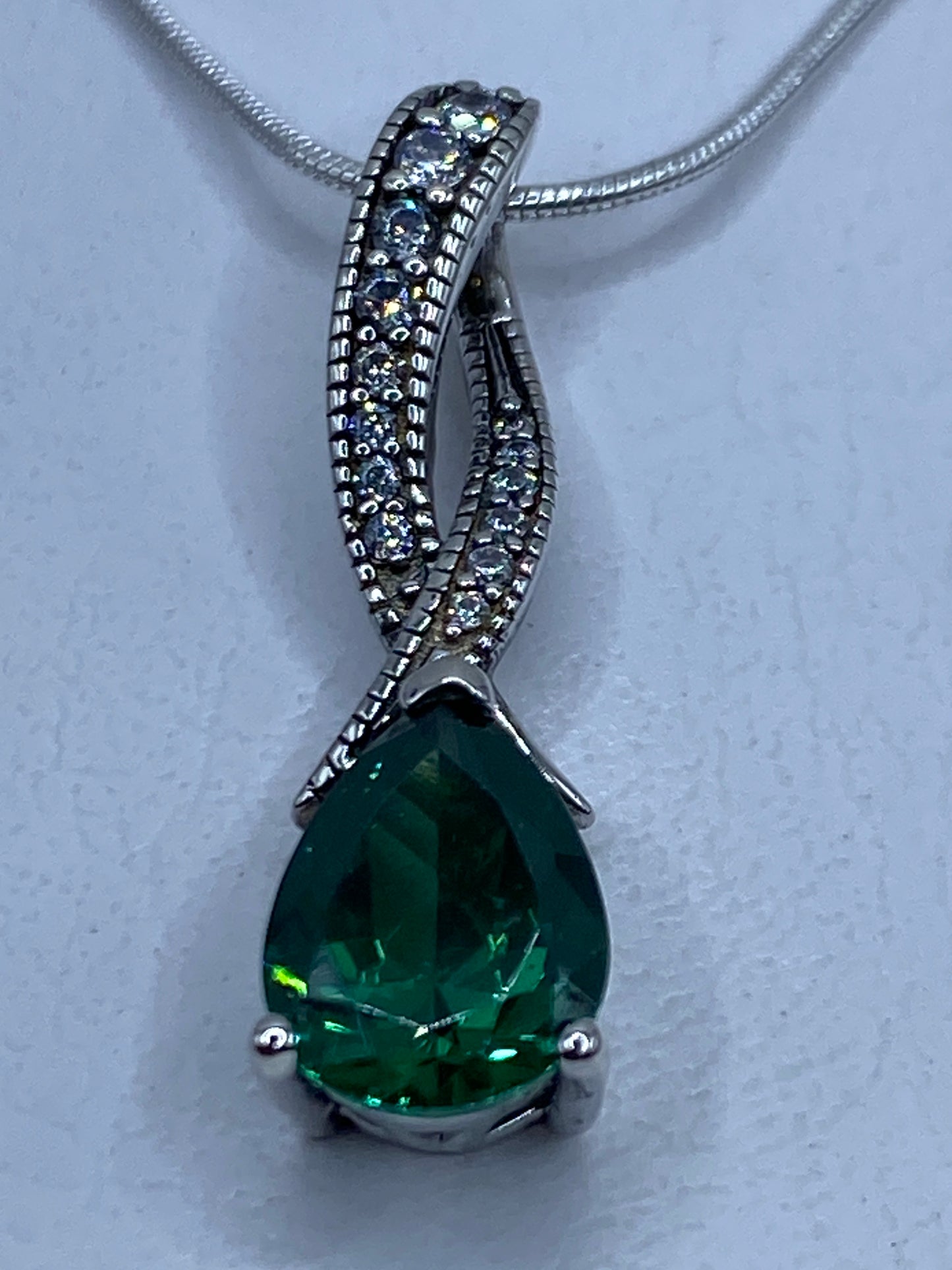 Dije de plata gota con circonia verde brillante engastada a mano, colgando de una cadena de plata