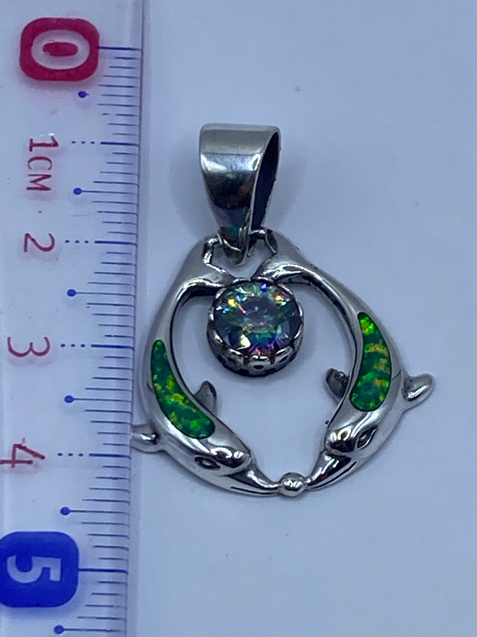 Dije medido con regla mostrando largo de 4.3 cm, sin cadena incluida