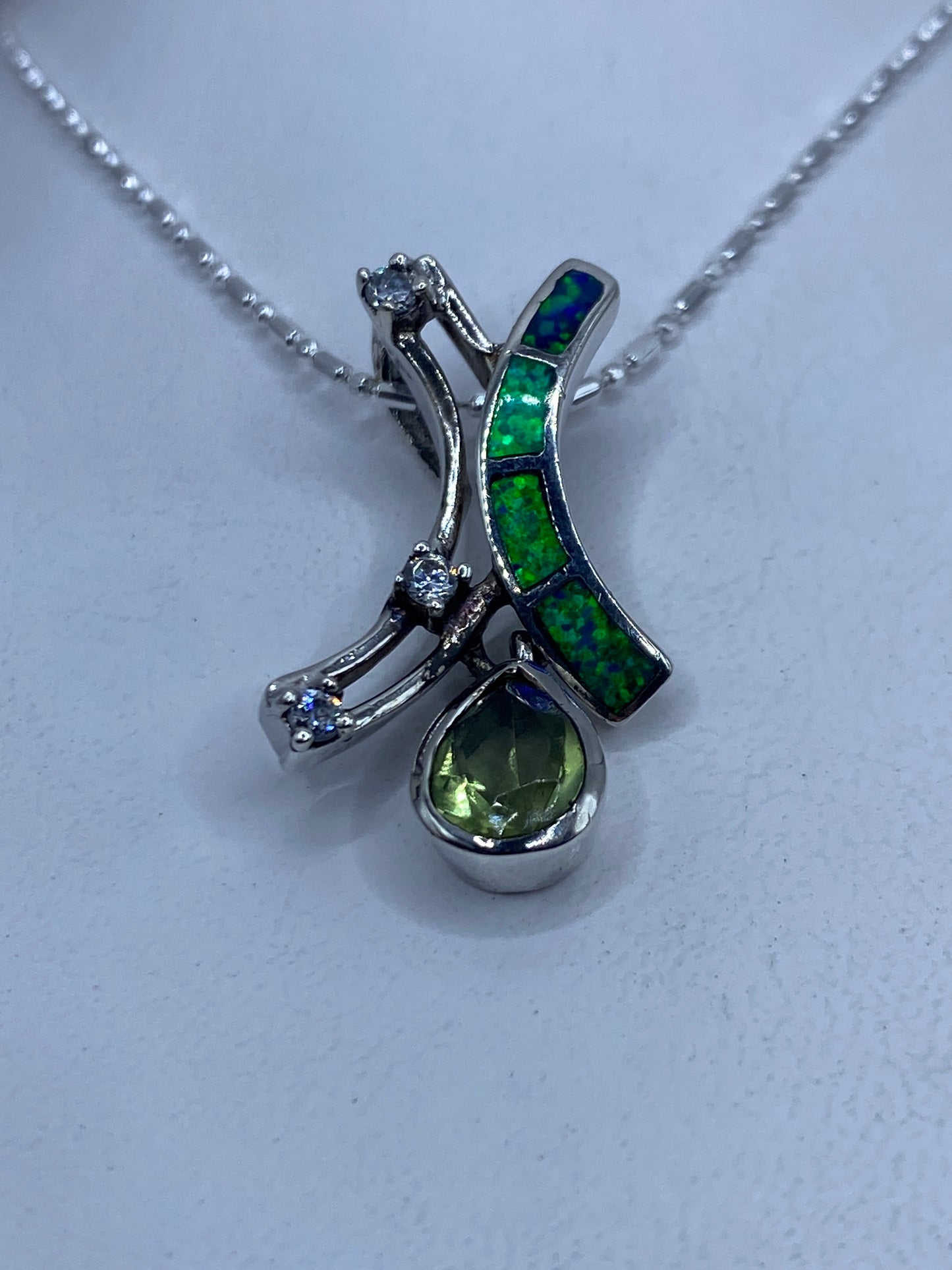 Dije de plata con opalo de fuego verde y dos cristales facetados, suspendido en cadena delgada