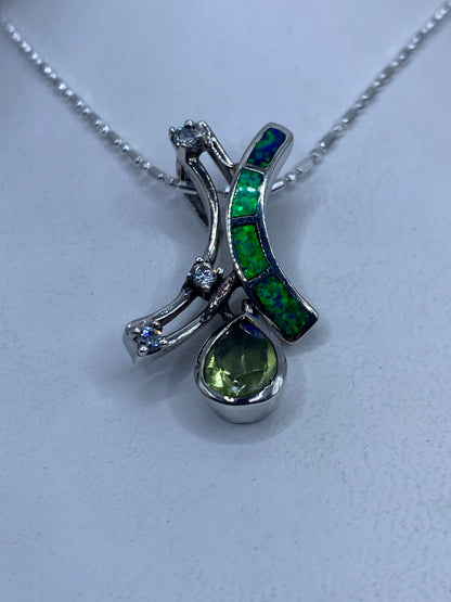 Dije de plata con opalo de fuego verde y dos cristales facetados, suspendido en cadena delgada