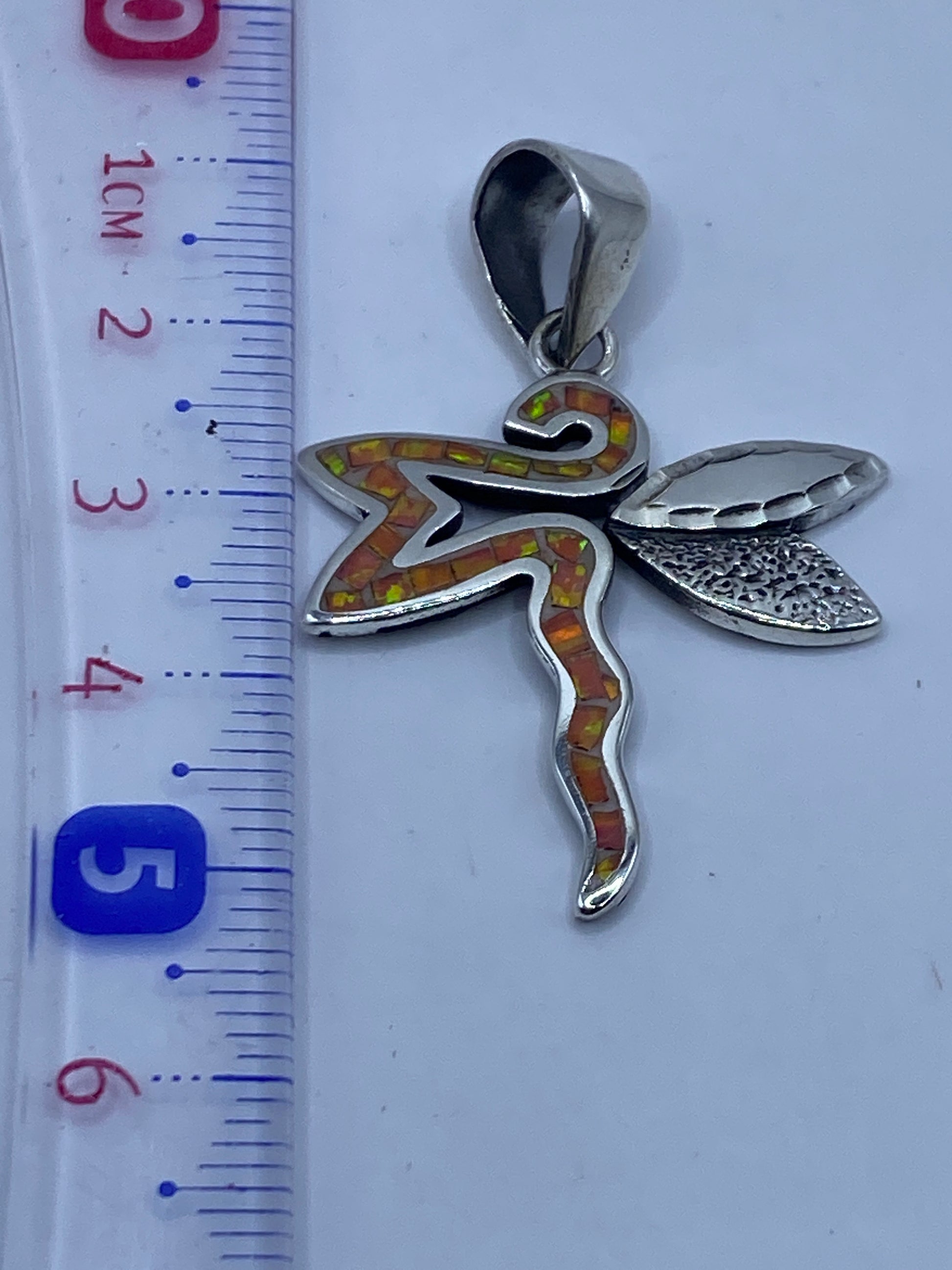 Medida del dije libélula: 5.1 cm de largo, sobre escala en centímetros