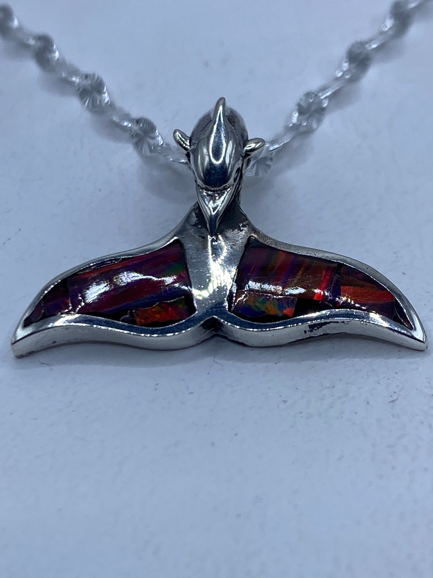 Dije de plata con ópalo de fuego multicolor en forma de cola de ballena, sobre cadena de plata con detalles florales