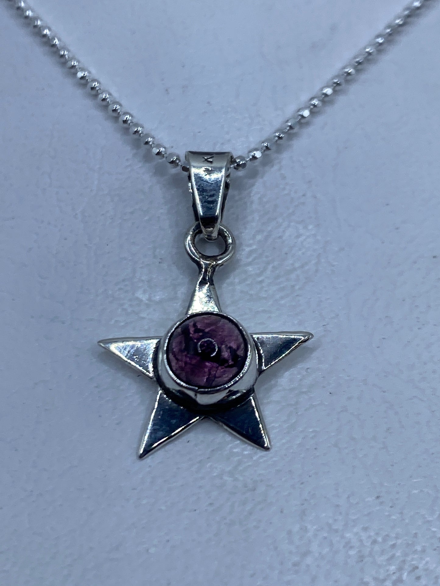 Dije de estrella de plata .925 con piedra morada engastada en el centro
