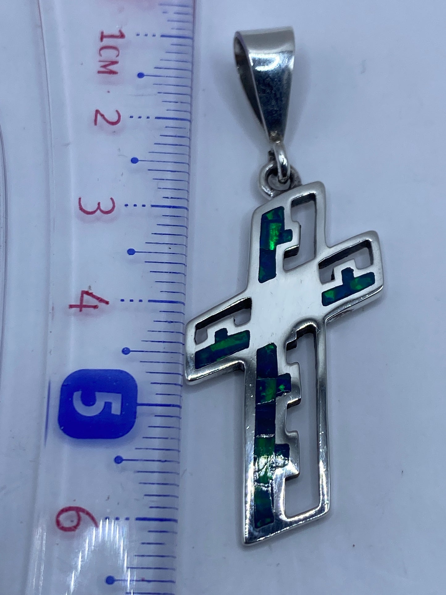 Dije cruz de 6.1 cm con Quinto .950 en reverso, sobre estuche blanco