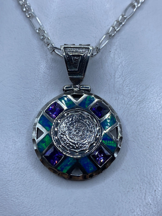 Dije circular de plata .950 con opalo de fuego azul y relieve prehispanico, colgando de cadena