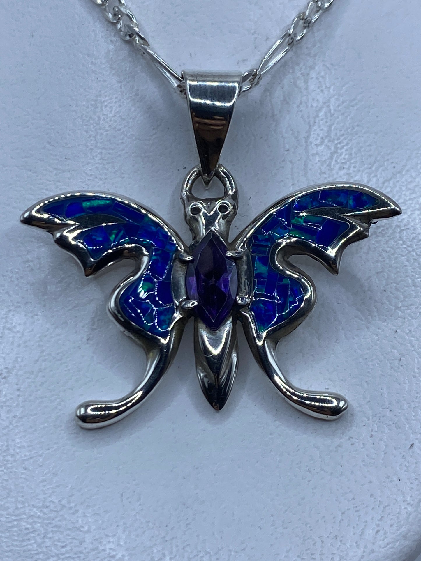 Dije de plata ópalo de fuego azul colgando de cadena plateada contra el pecho