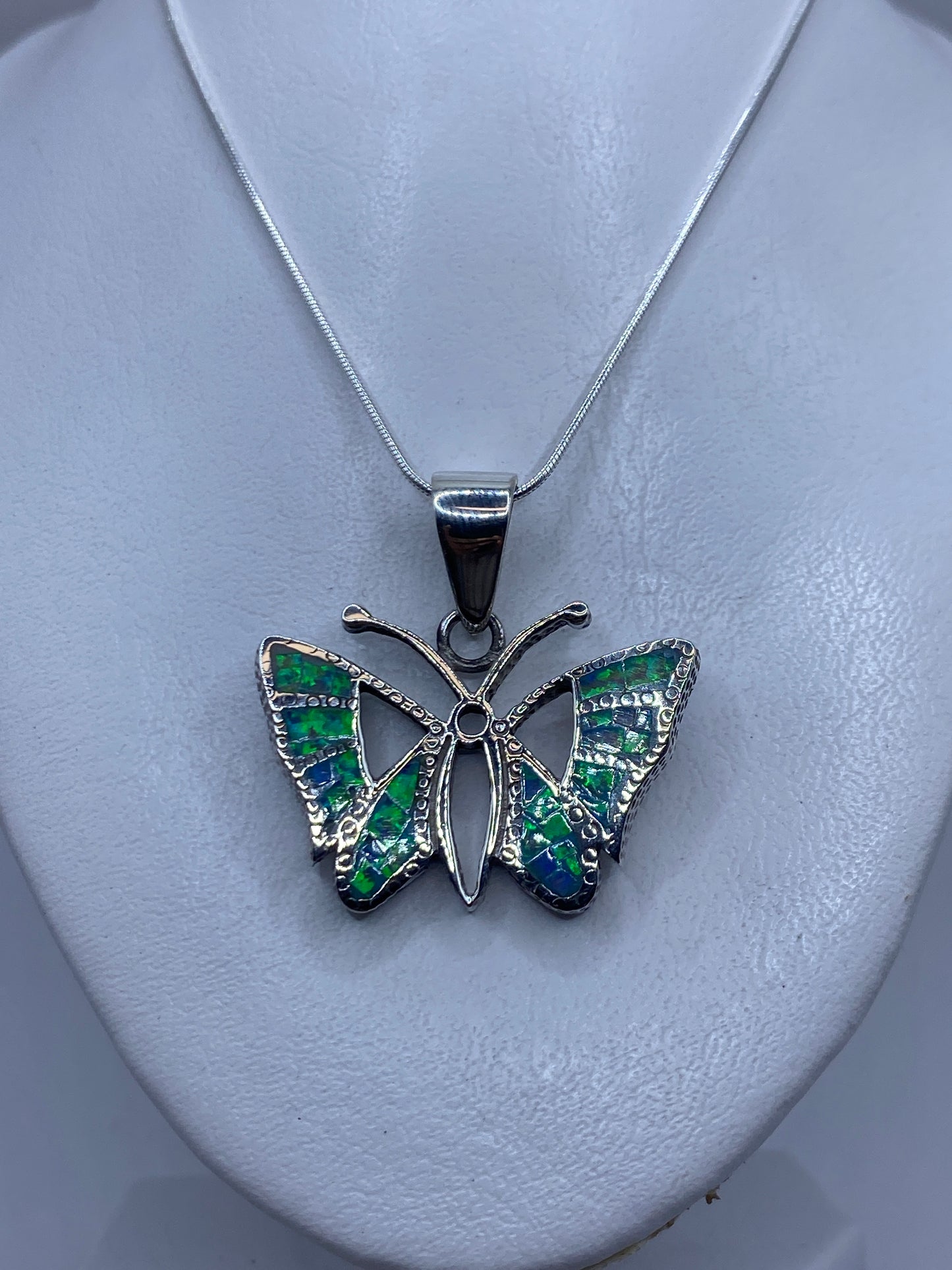 Detalle del ópalo de fuego azul con reflejos verdes en el dije mariposa de Taxco