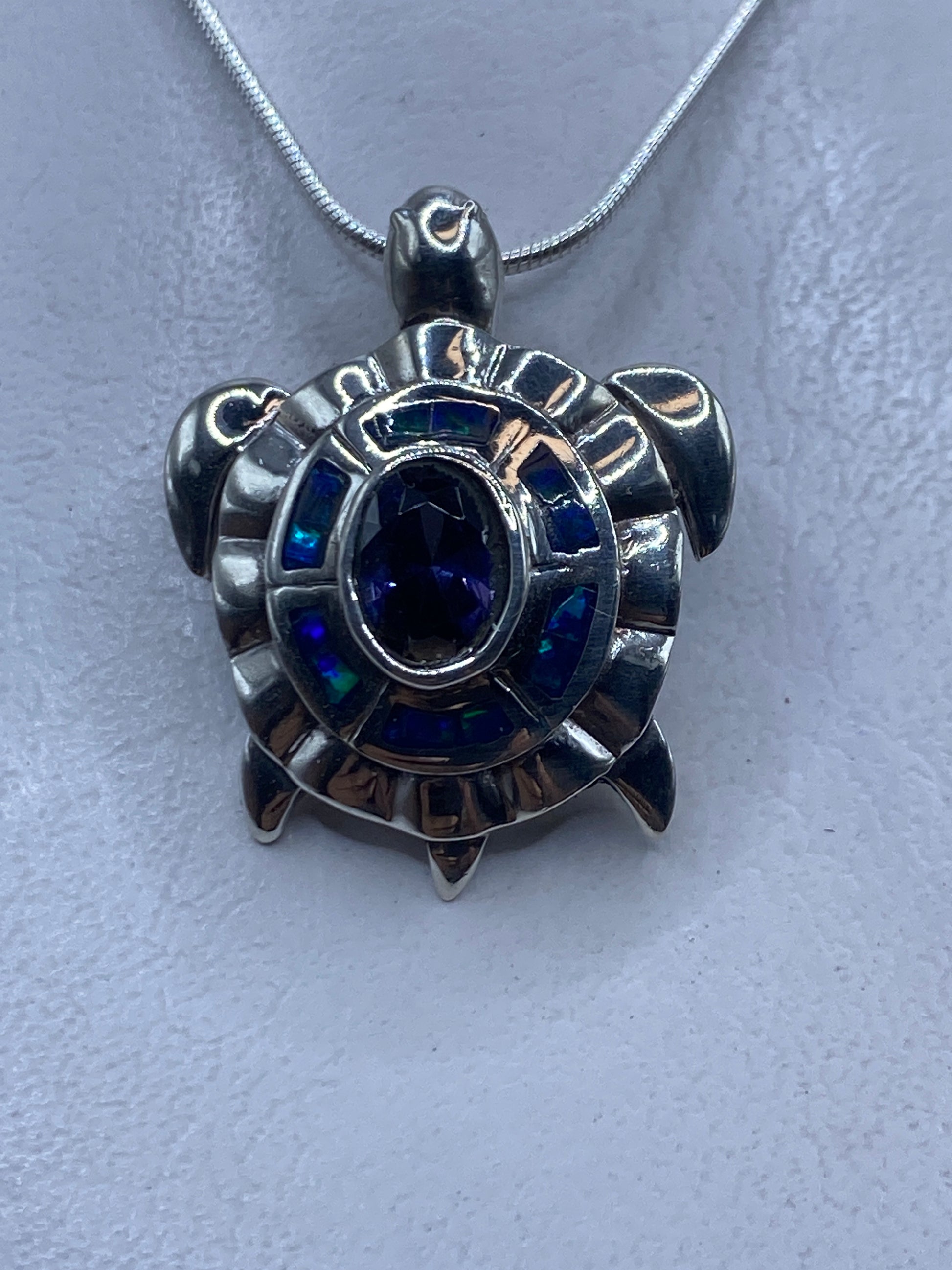 Dije de plata con ópalo de fuego azul engastado, colgando de cadena de plata