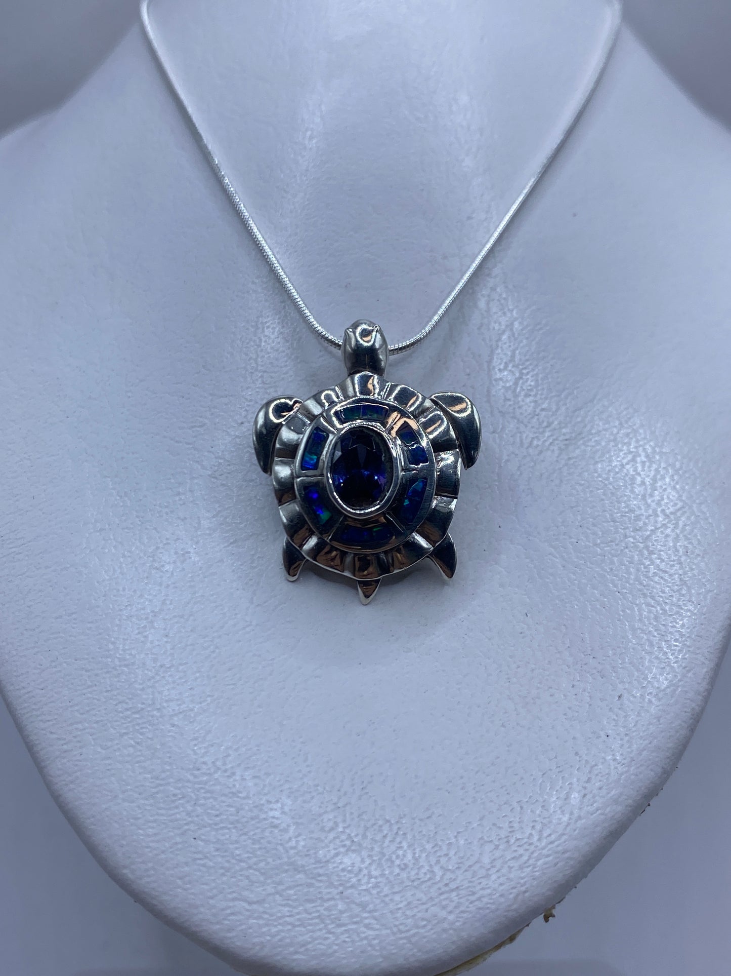 Vista frontal del dije de 3.5 cm con ópalo azul y patrones de relieve en plata