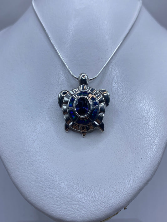 Vista frontal del dije de 3.5 cm con ópalo azul y patrones de relieve en plata