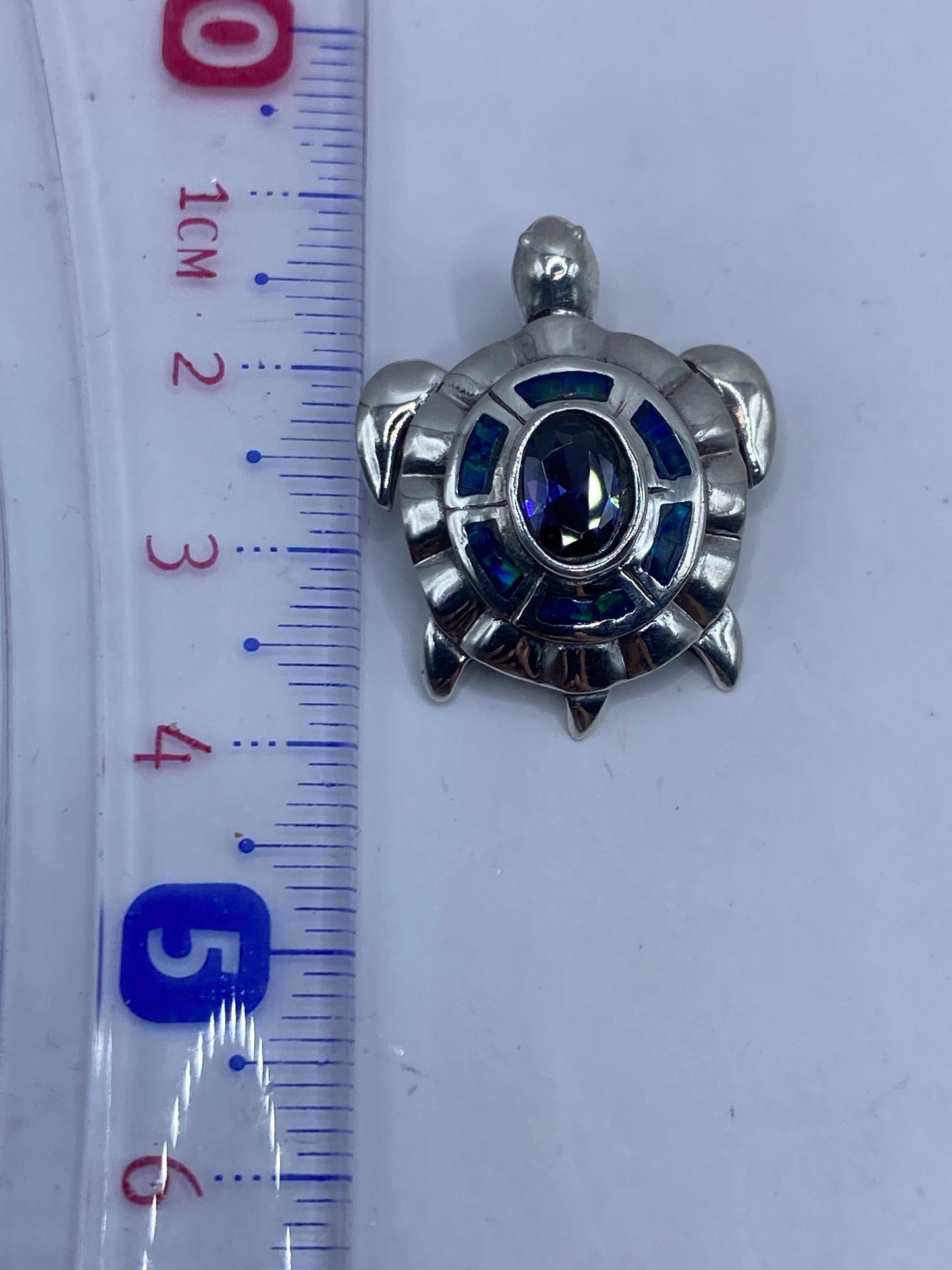 Dije en forma de tortuga con ópalo de fuego azul sobre fondo gris
