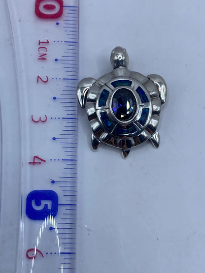 Dije en forma de tortuga con ópalo de fuego azul sobre fondo gris