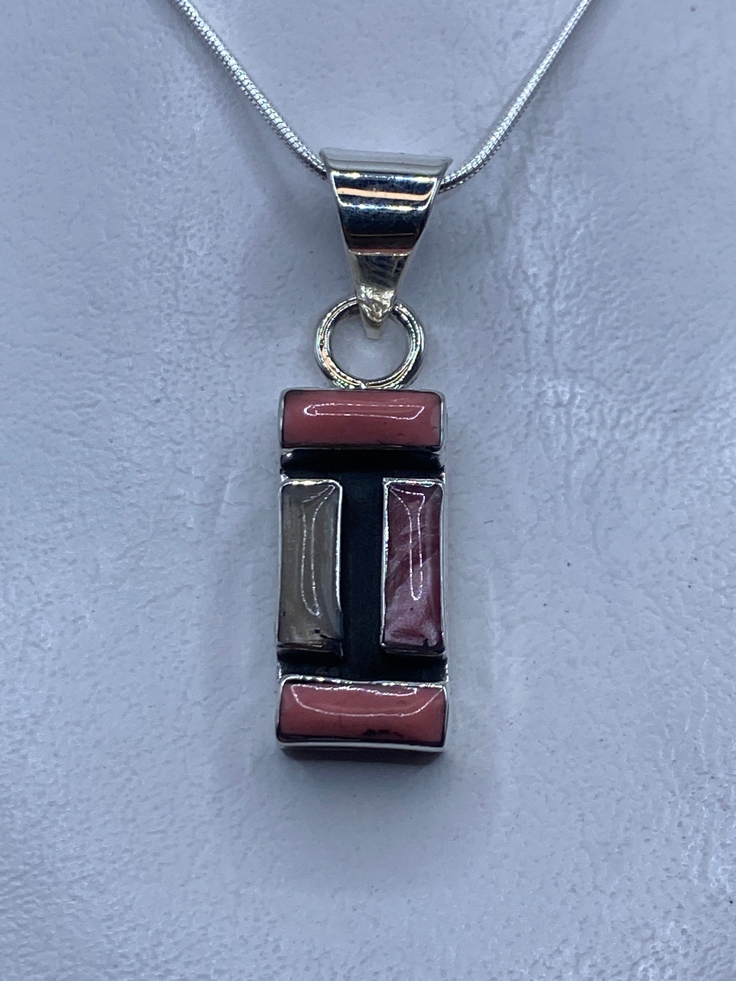 Dije de plata con coral rosa engastado a mano, colgando de cadena plateada