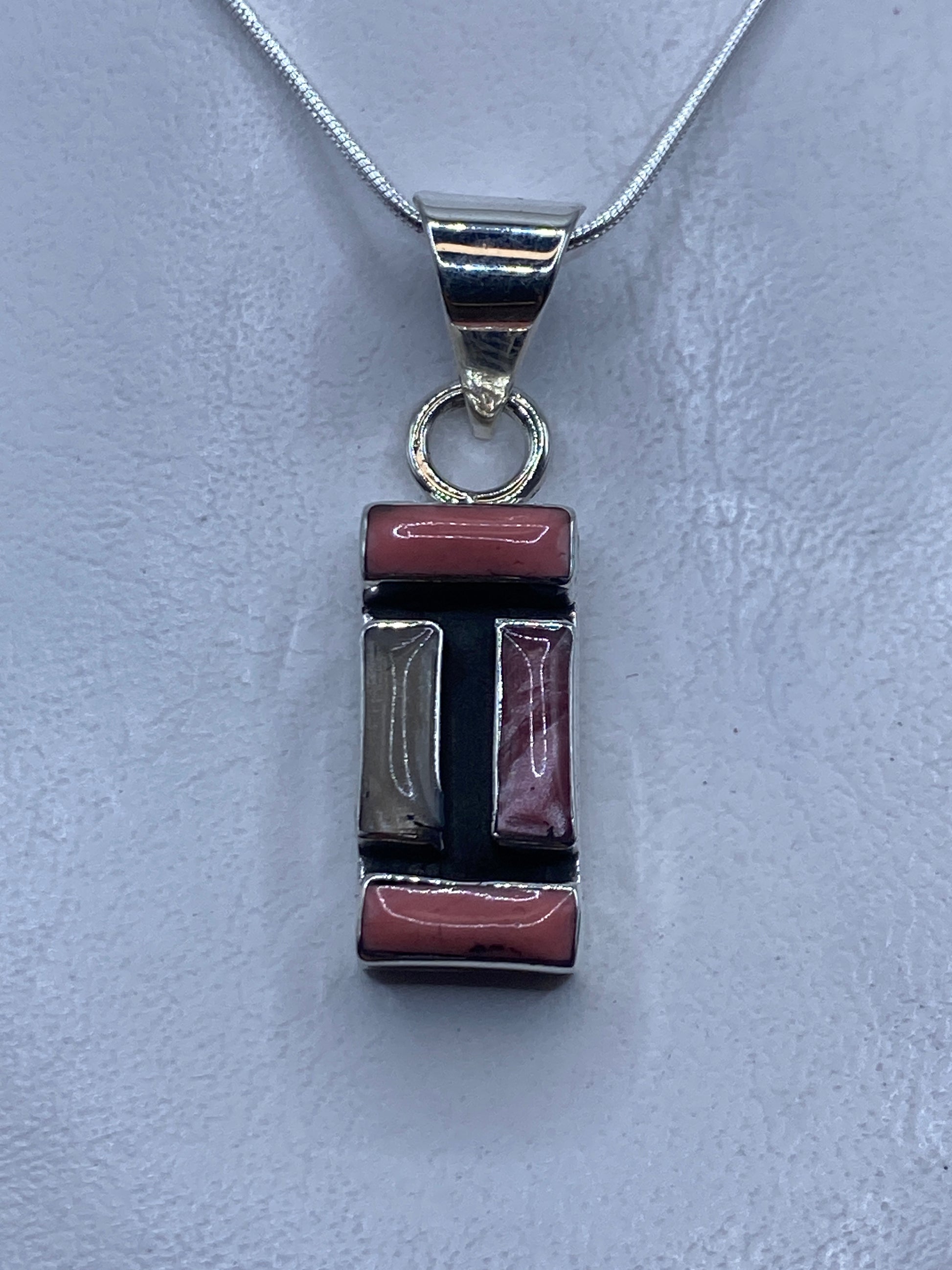 Dije de plata con coral rosa engastado a mano, colgando de cadena plateada