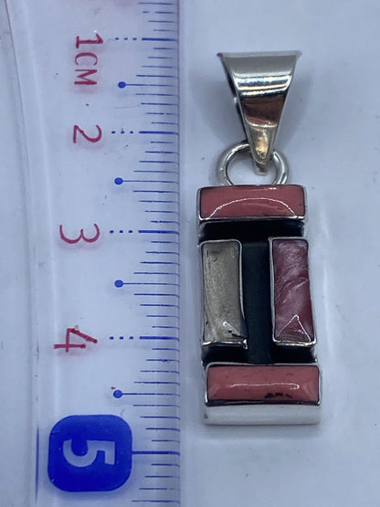Dije de coral sobre fondo blanco, al lado de regla mostrando medida de 4.5 cm