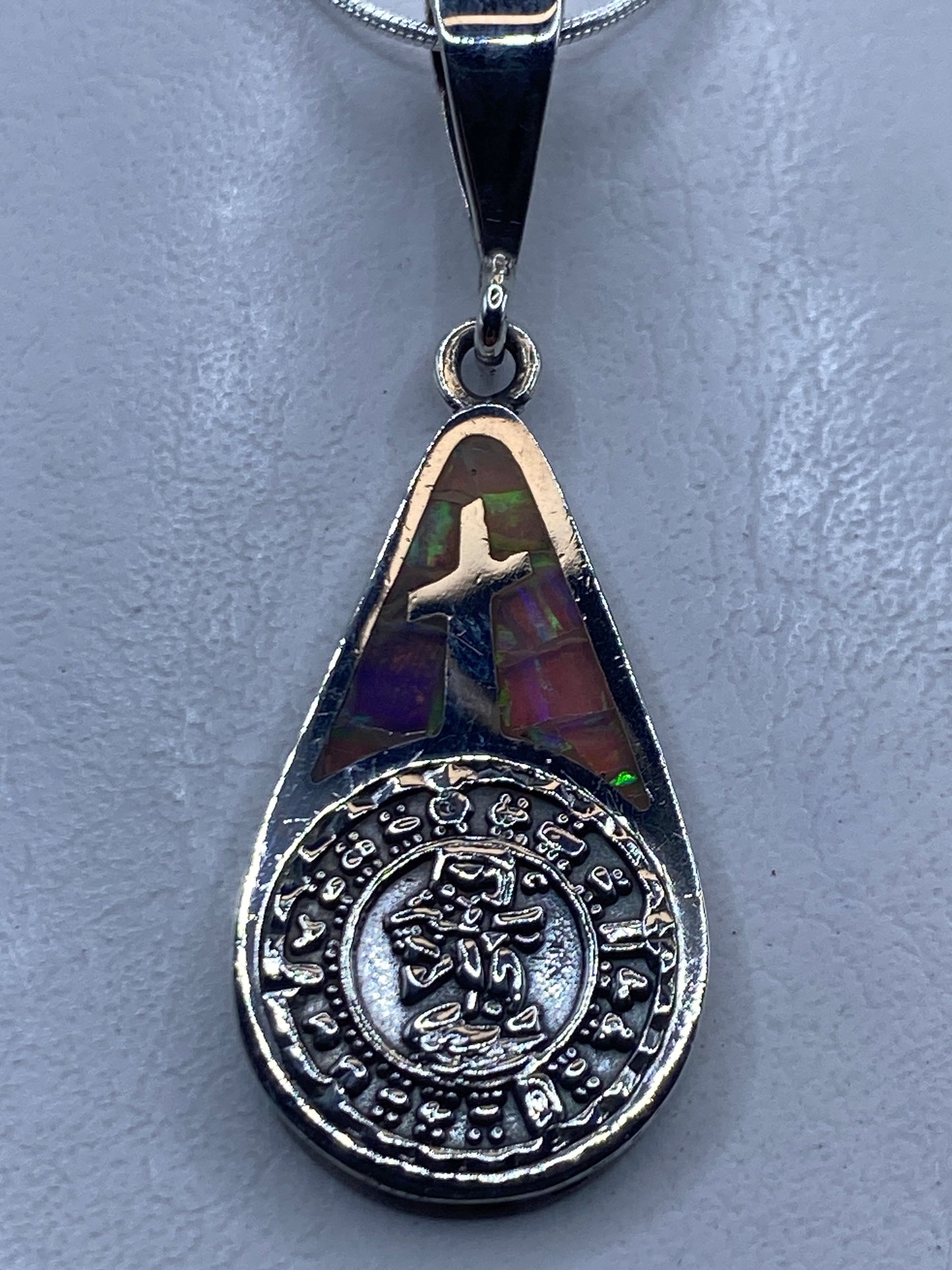 Dije cruz de plata .950 con opalo de fuego multicolor e inscripción zodiacal