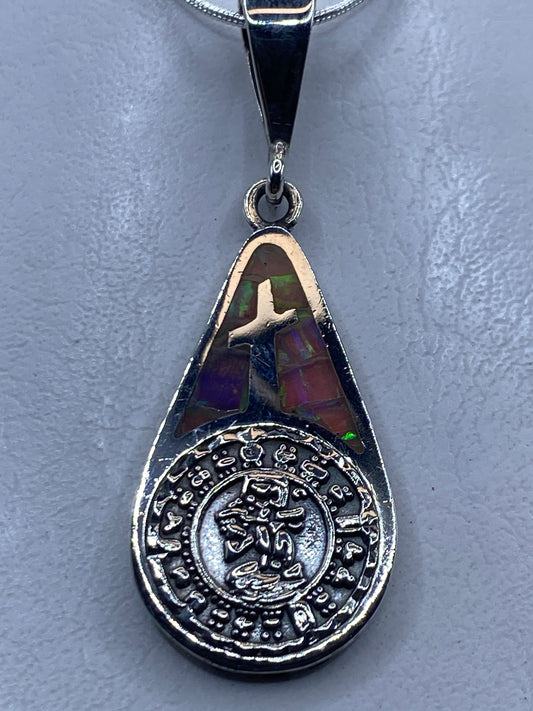 Dije cruz de plata .950 con opalo de fuego multicolor e inscripción zodiacal