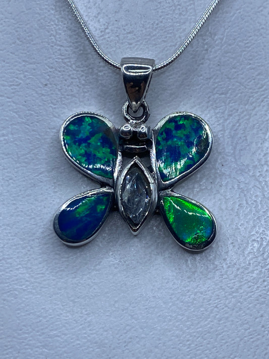 Dije mariposa de plata .925 con ópalo de fuego azul, engaste a mano, sobre fondo blanco