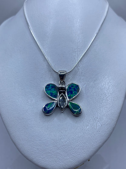 Detalle del dije mariposa mostrando el juego de color azul y verde del ópalo de fuego