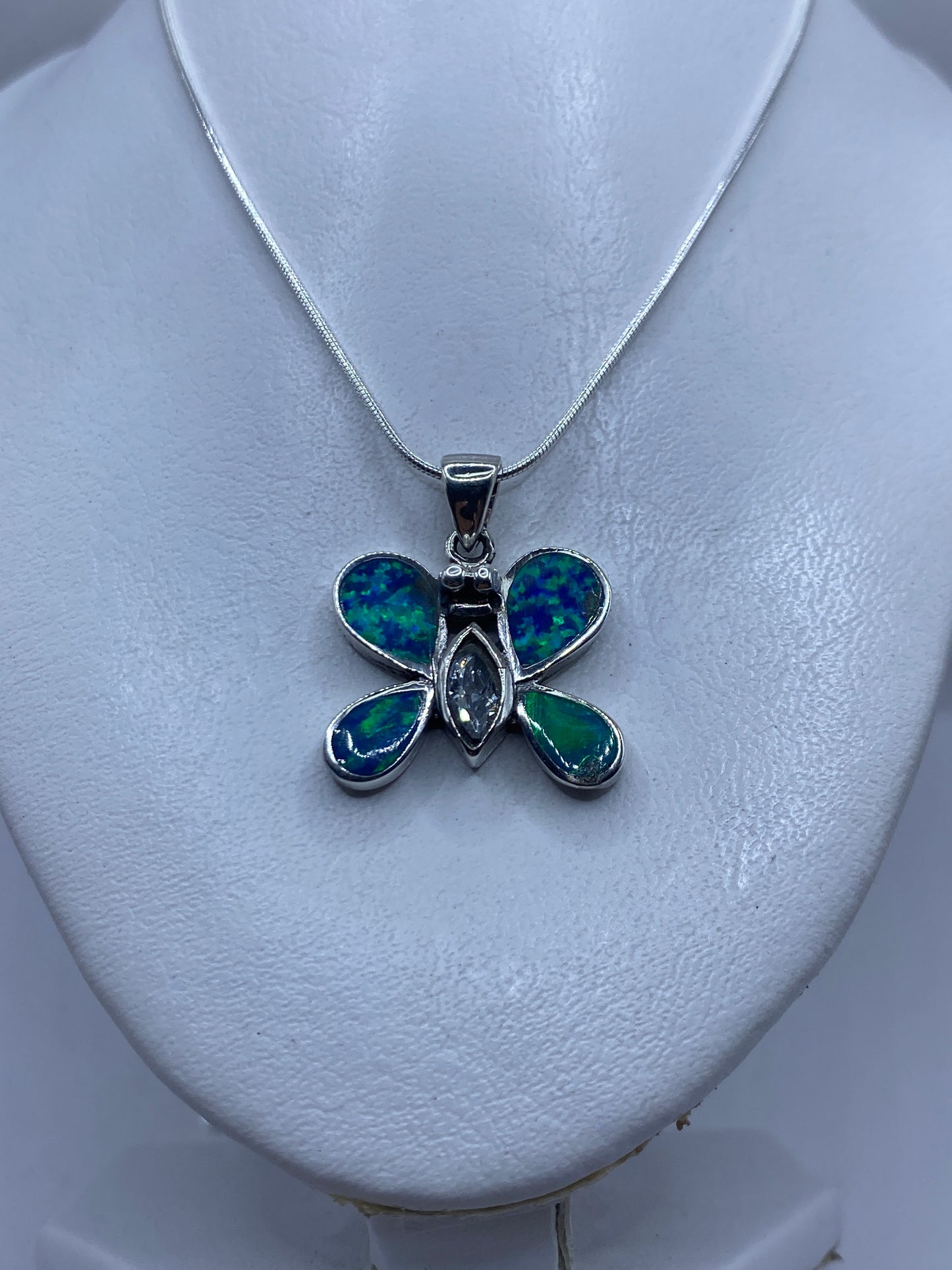 Mariposa de plata con granulado en las alas y ópalo azul en el centro, portada sobre piel