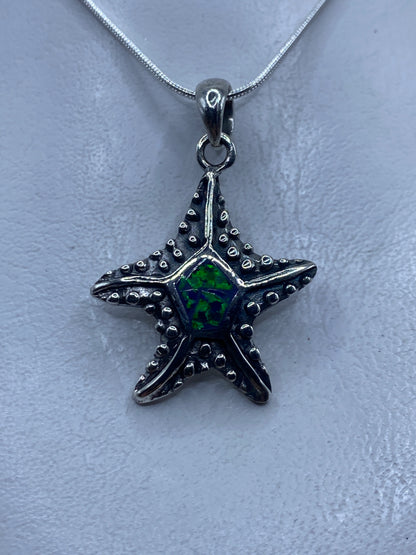 Dije de estrella de mar en plata .950 con ópalo de fuego verde engastado en el centro