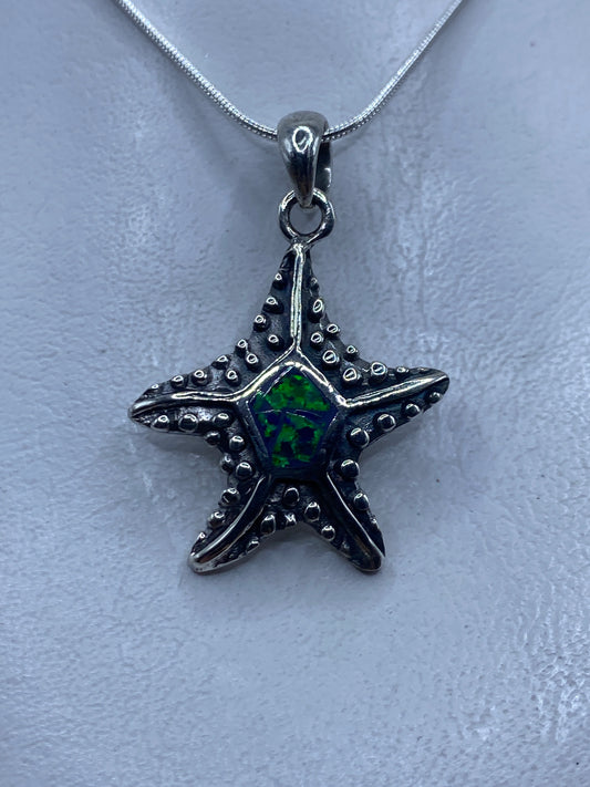 Dije de estrella de mar en plata .950 con ópalo de fuego verde engastado en el centro