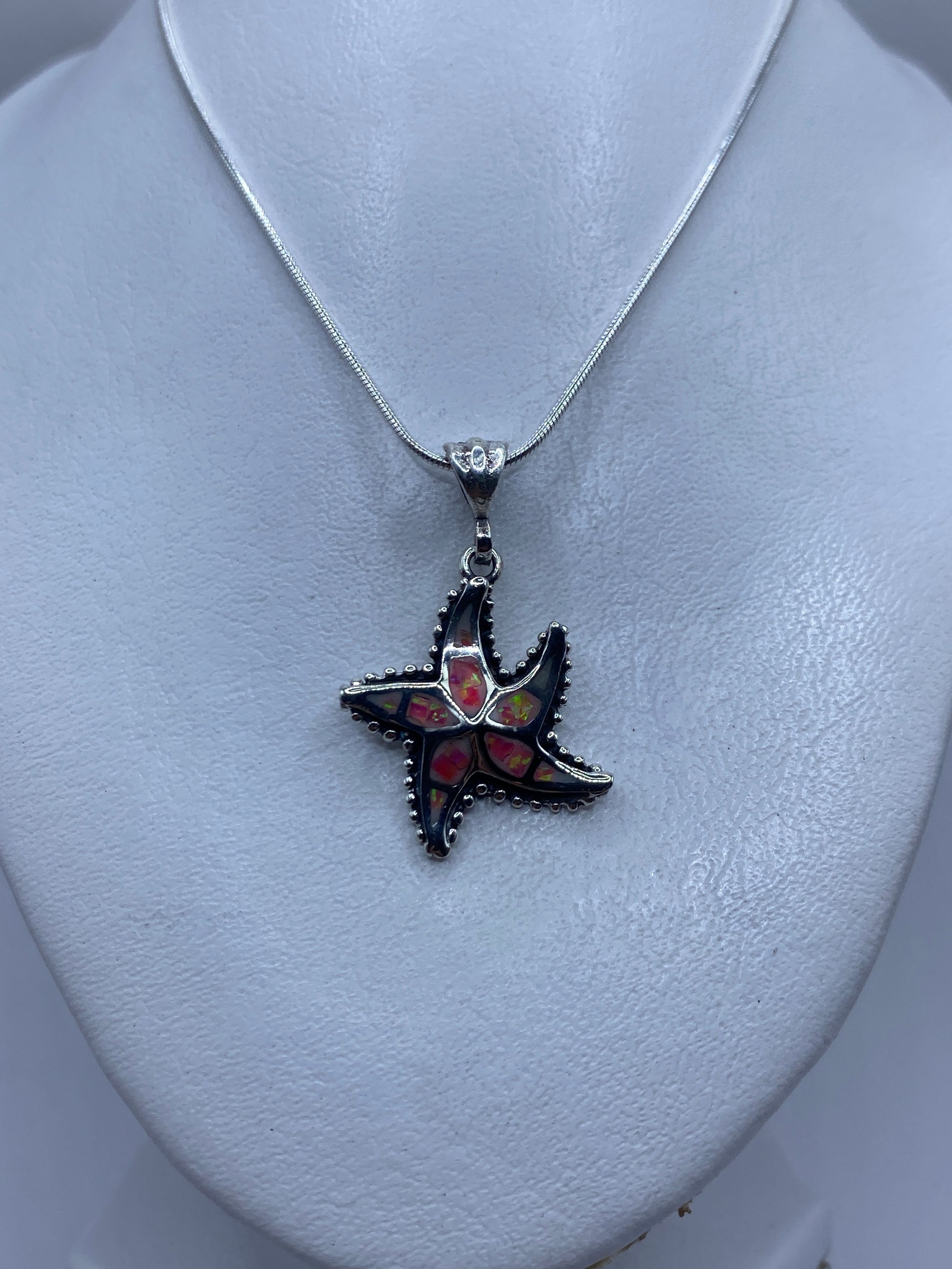 Detalle del engaste artesanal de ópalo de fuego rosa en las puntas de la estrella de plata