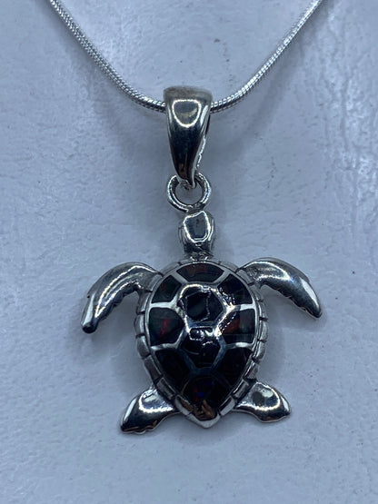 Dije de tortuga marina en plata .925 con ópalo de fuego engastado, colgando de una cadena de plata