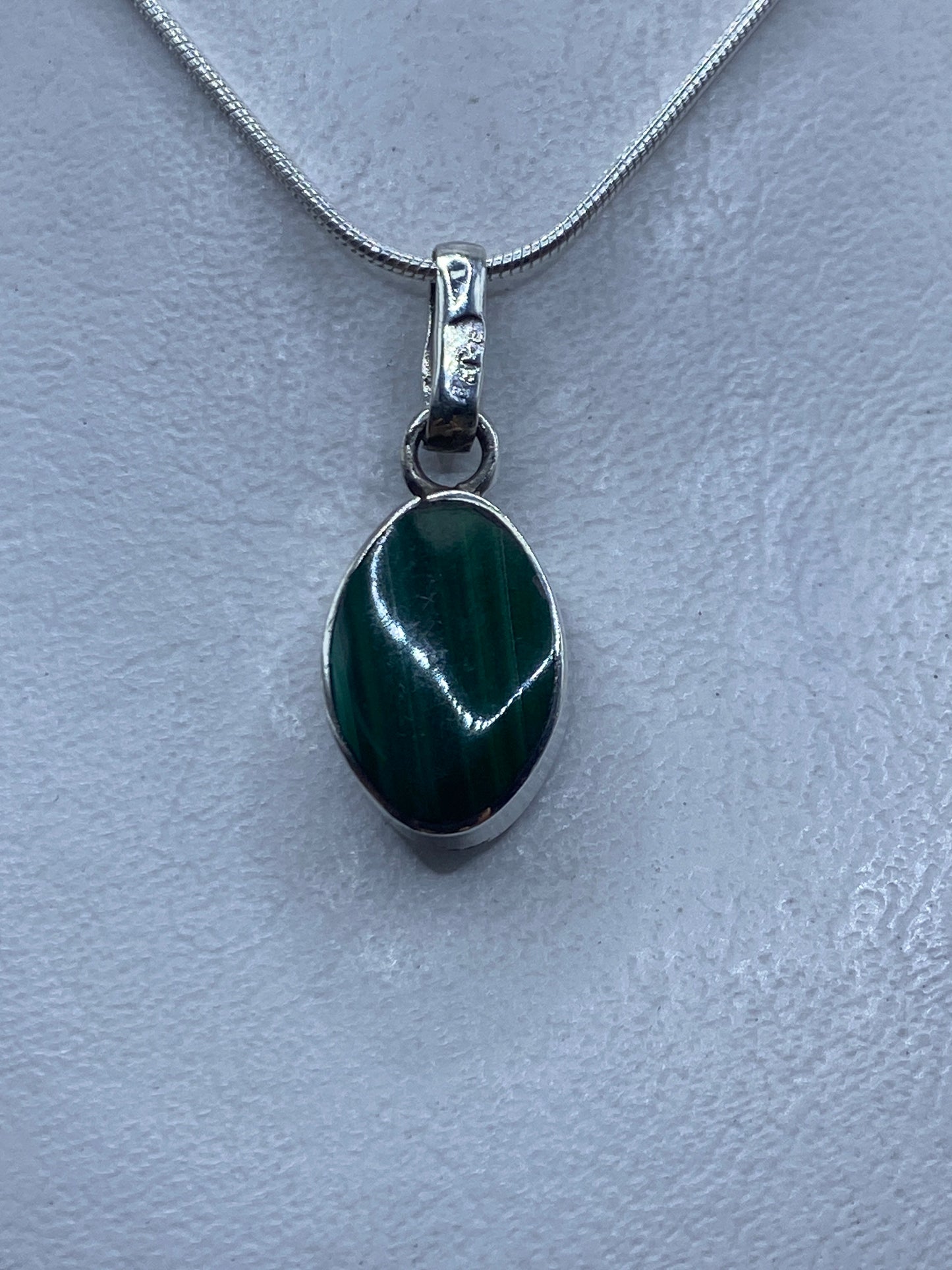 Detalle del dije mostrando el ópalo de fuego natural con reflejos verdes y el engaste de plata