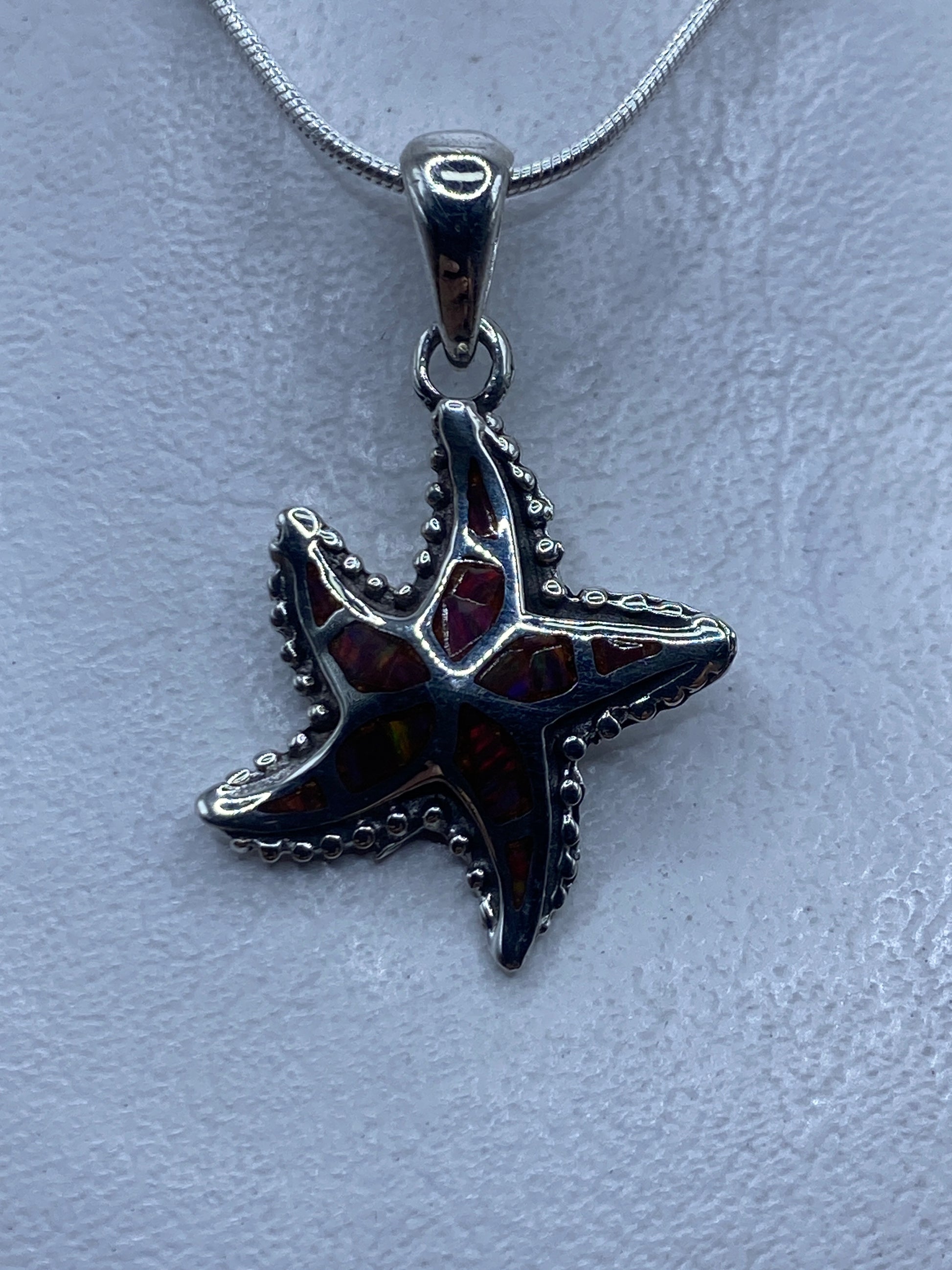 Dije de estrella de mar en plata .950 con ópalo de fuego rojo colgado en cadena de plata