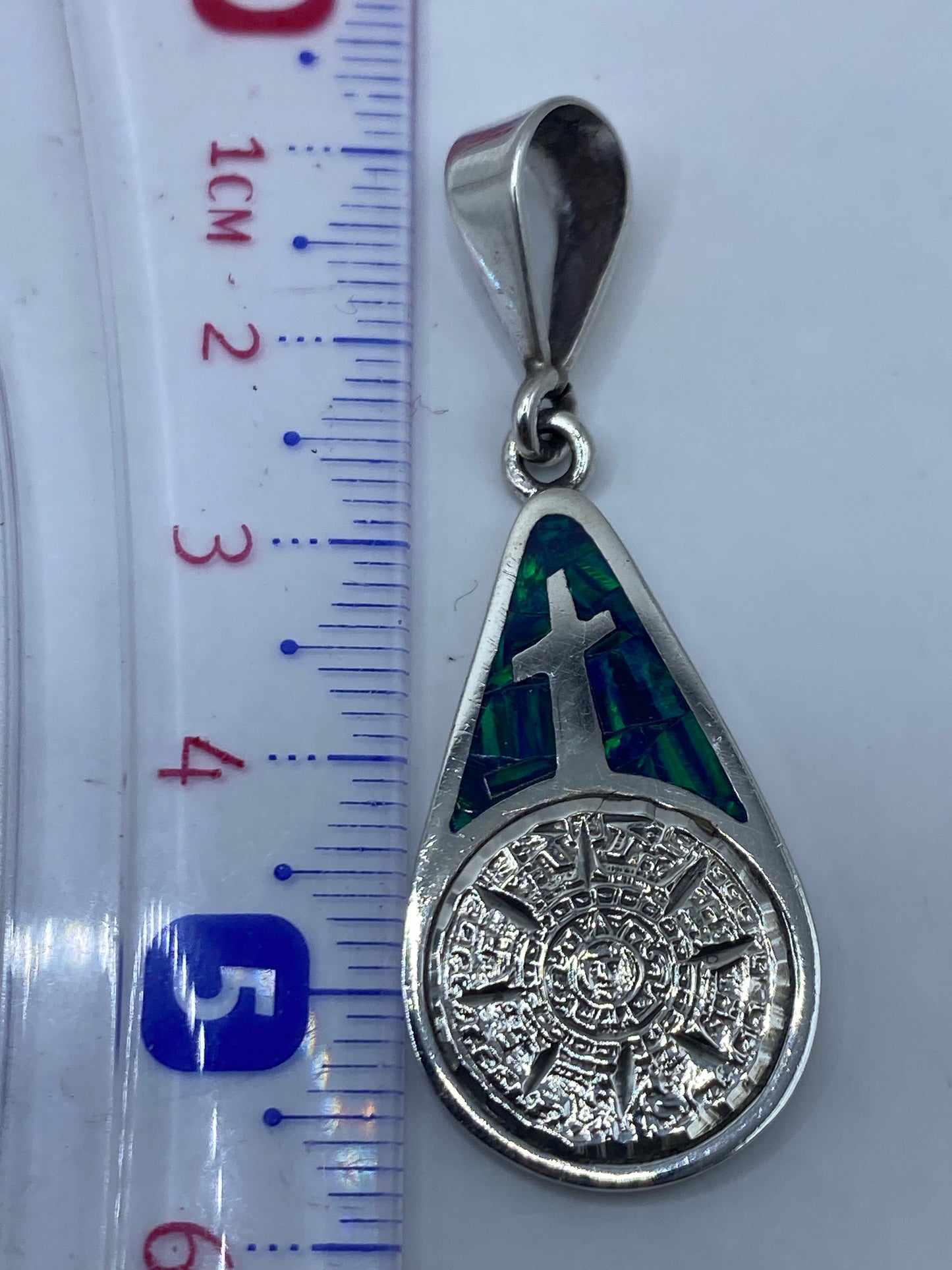 Dije sobre fondo blanco mostrando el tamaño real (5.7 cm) y el Quinto .950