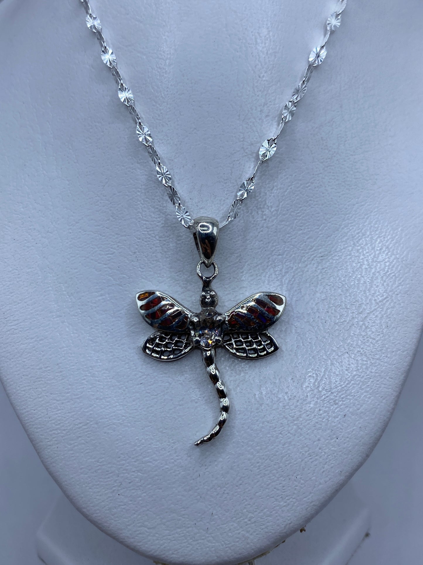 Detalle del ópalo de fuego multicolor con tonos ámbar y rojo en la libélula de plata