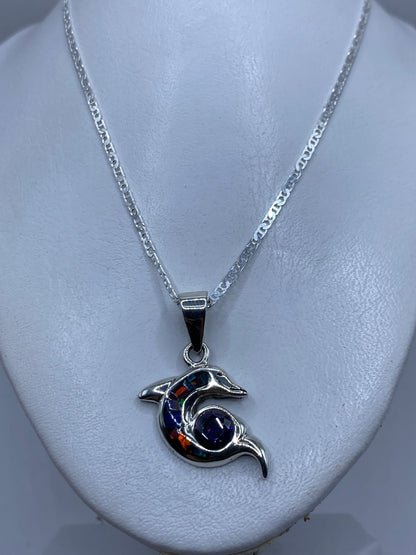 Detalle del delfín de plata mostrando el ópalo de fuego engastado en tonos naranja, azul y verde