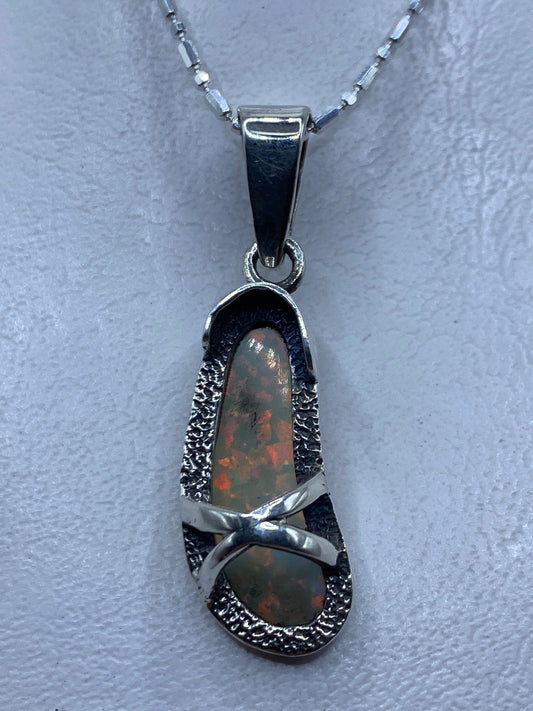 Dije de plata con ópalo de fuego multicolor mostrando reflejos rojos, naranjas y verdes