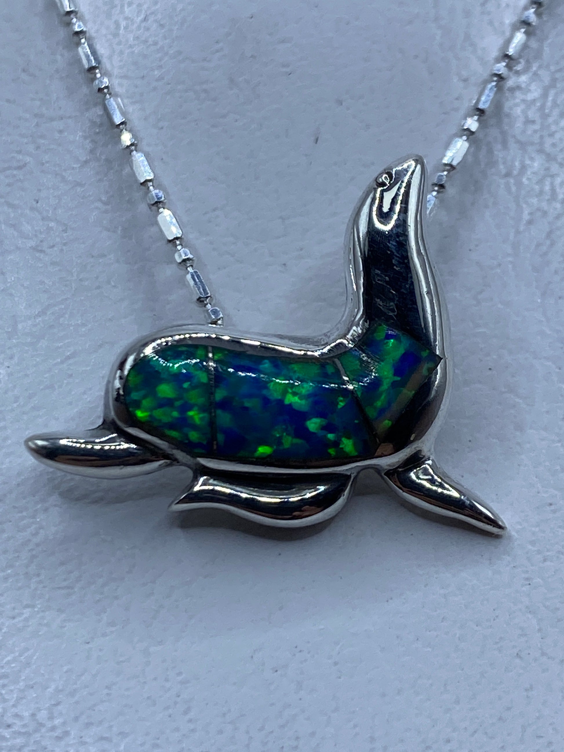 Dije de foca en plata .925 con ópalo de fuego azul, colgando de cadena de eslabón en plata