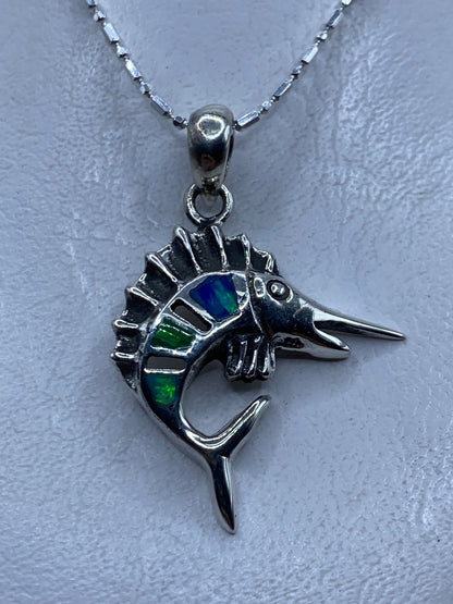Dije de pez espada en plata .950 con ópalo de fuego multicolor, mostrado en el pecho sobre cadena