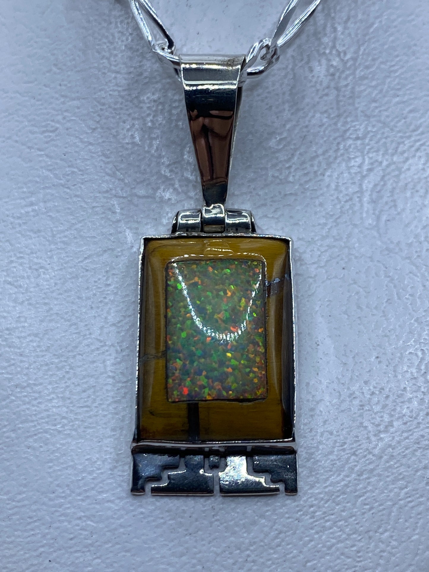 Dije de plata prehispánico de 4.7 cm con piedra engastada y motivos grabados, colgando en cadena de plata