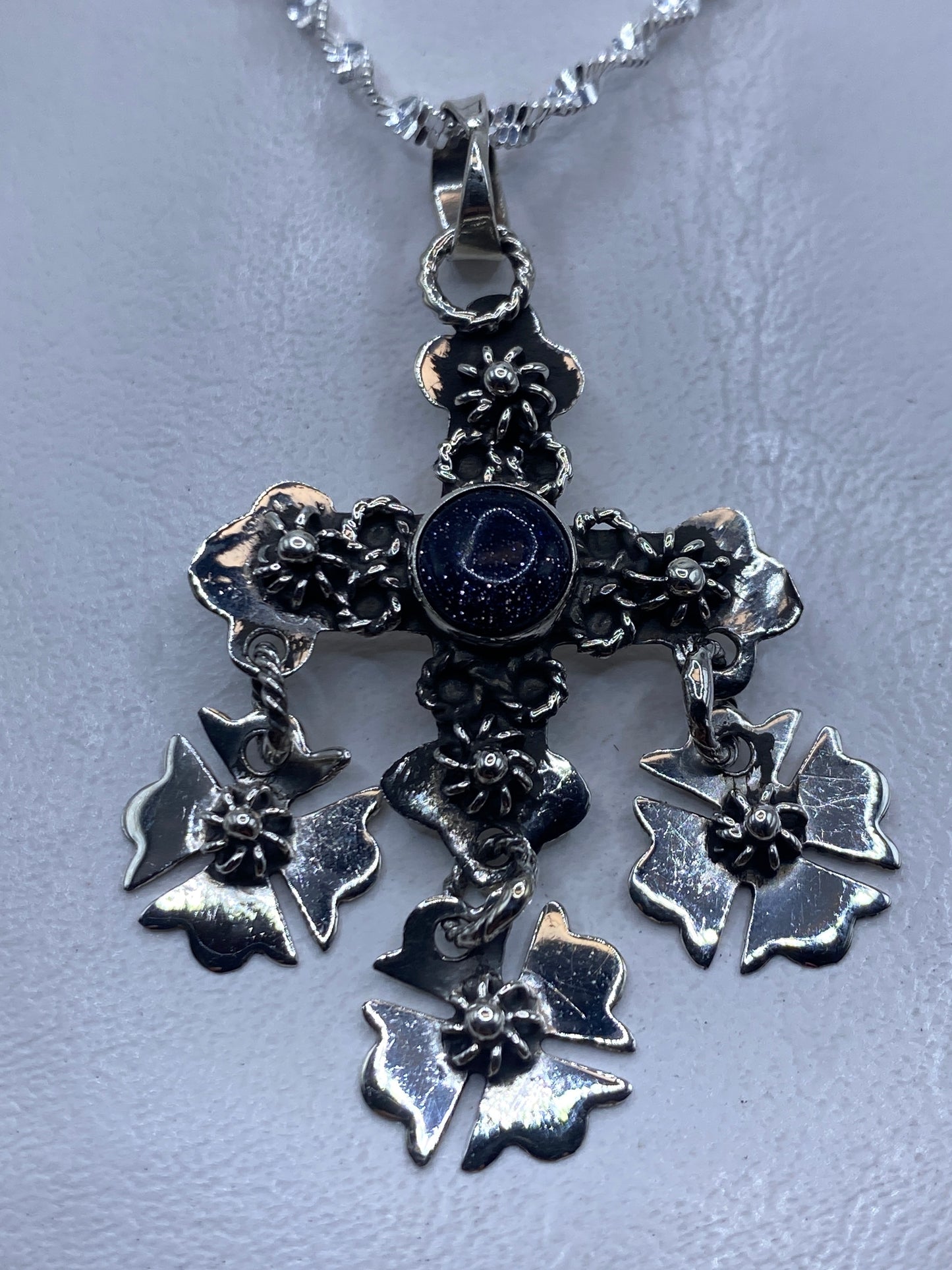 Dije cruz floral de plata .925 con piedra morada colgando en cadena