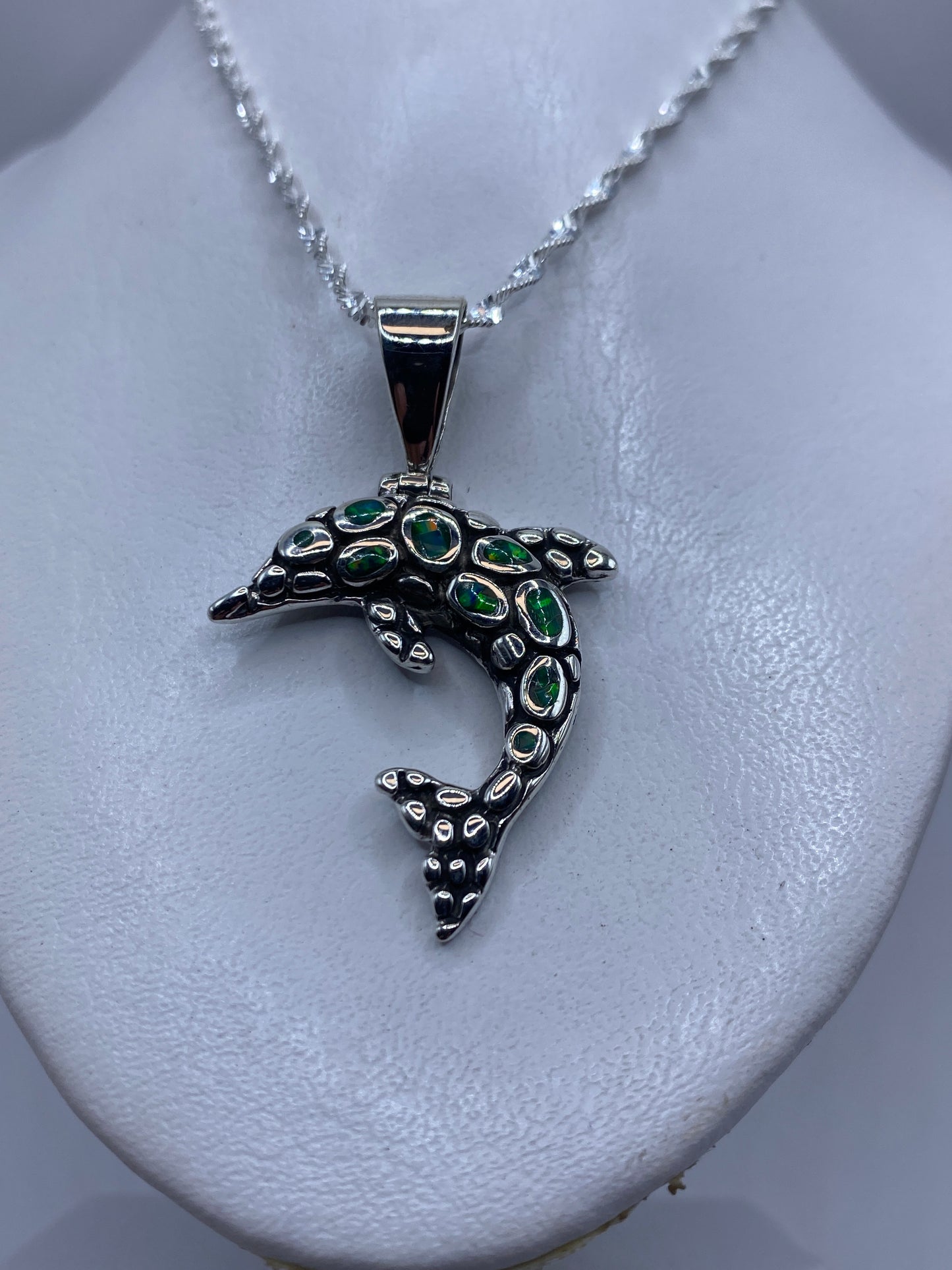 Detalle de la incrustación de piedra del ópalo en el delfín de plata