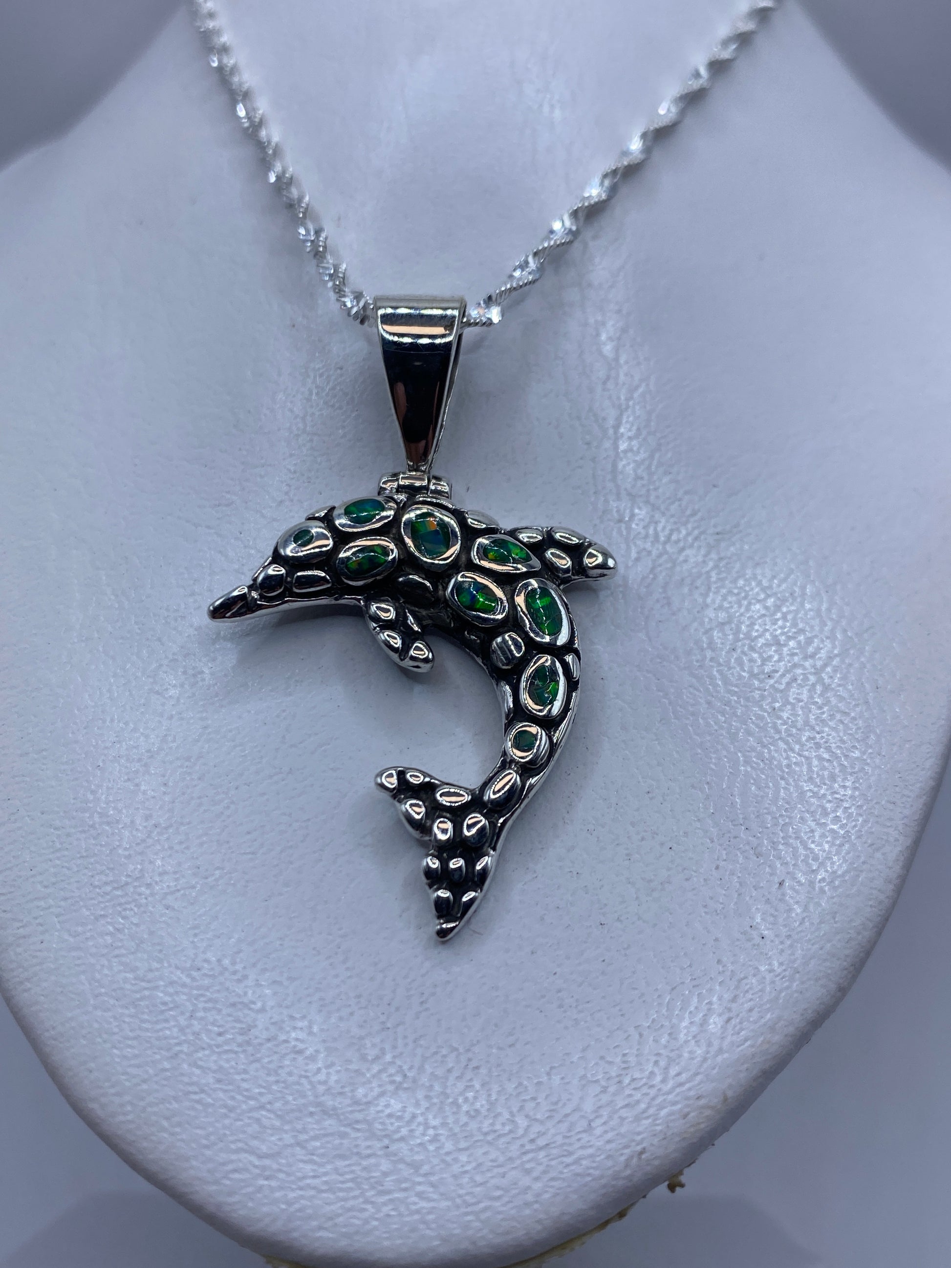 Detalle de la incrustación de piedra del ópalo en el delfín de plata