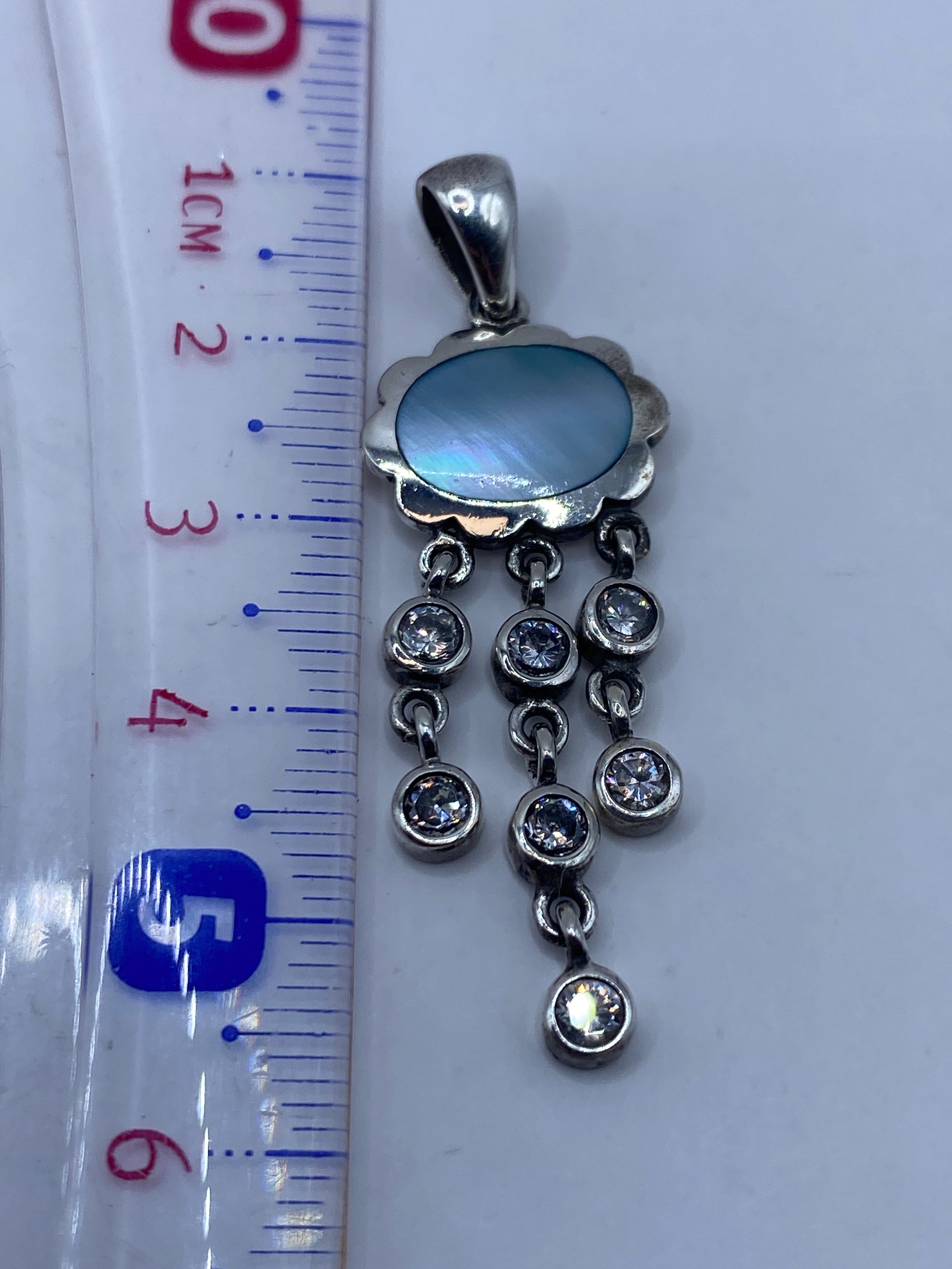 Dije de 5.6 cm de largo junto a regla de medición