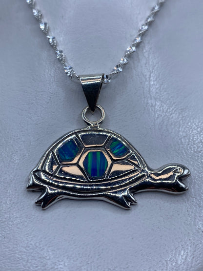 Dije de plata tortuga con ópalo de fuego azul, colgado de una cadena retorcida de plata .925