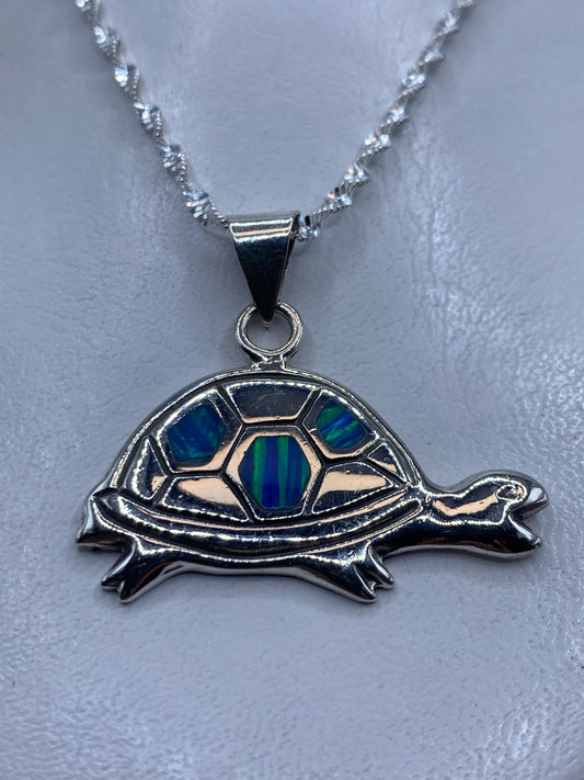 Dije de plata tortuga con ópalo de fuego azul, colgado de una cadena retorcida de plata .925