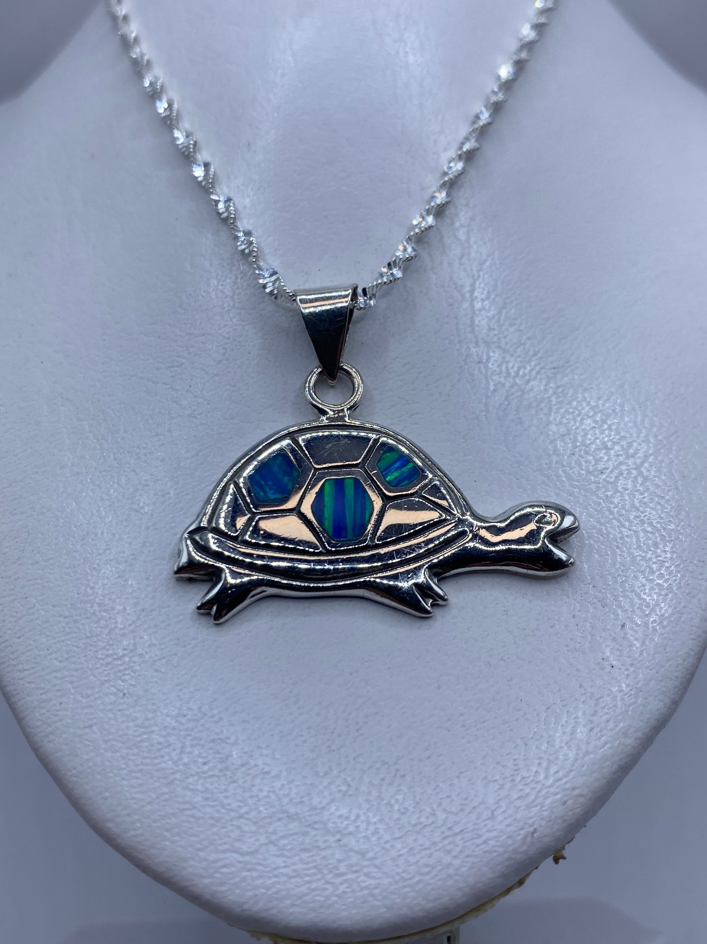 Tortuga de plata en primer plano mostrando el ópalo de fuego incrustado en tonos azul y verde