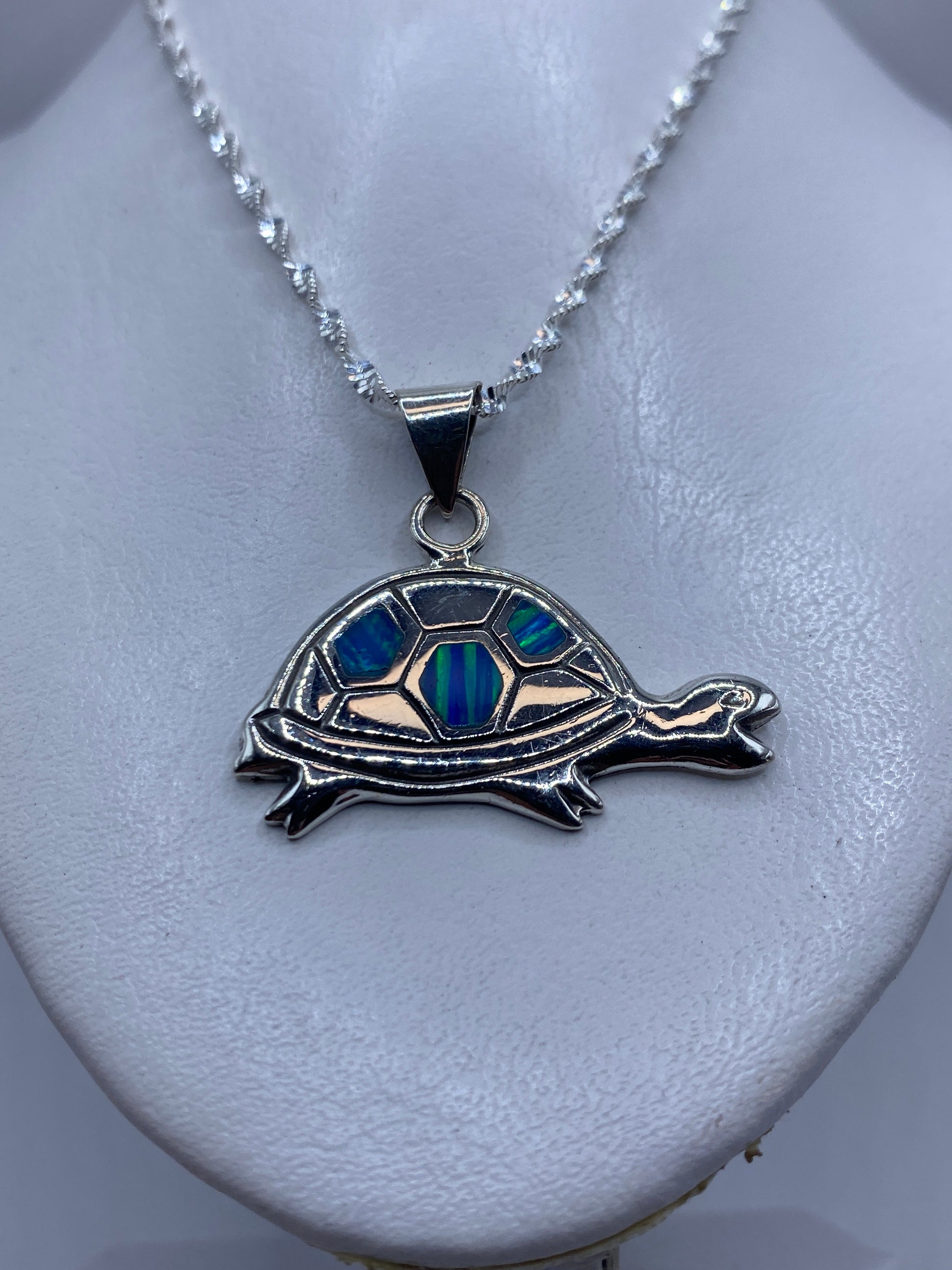 Tortuga de plata en primer plano mostrando el ópalo de fuego incrustado en tonos azul y verde