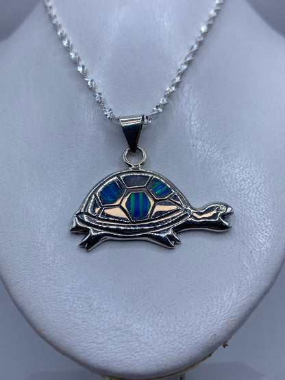 Tortuga de plata en primer plano mostrando el ópalo de fuego incrustado en tonos azul y verde