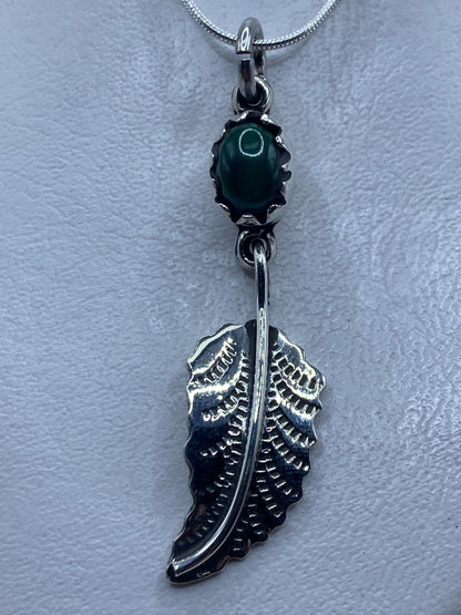 Dije de plata con malaquita verde y diseño de ala colgando de cadena serpentina