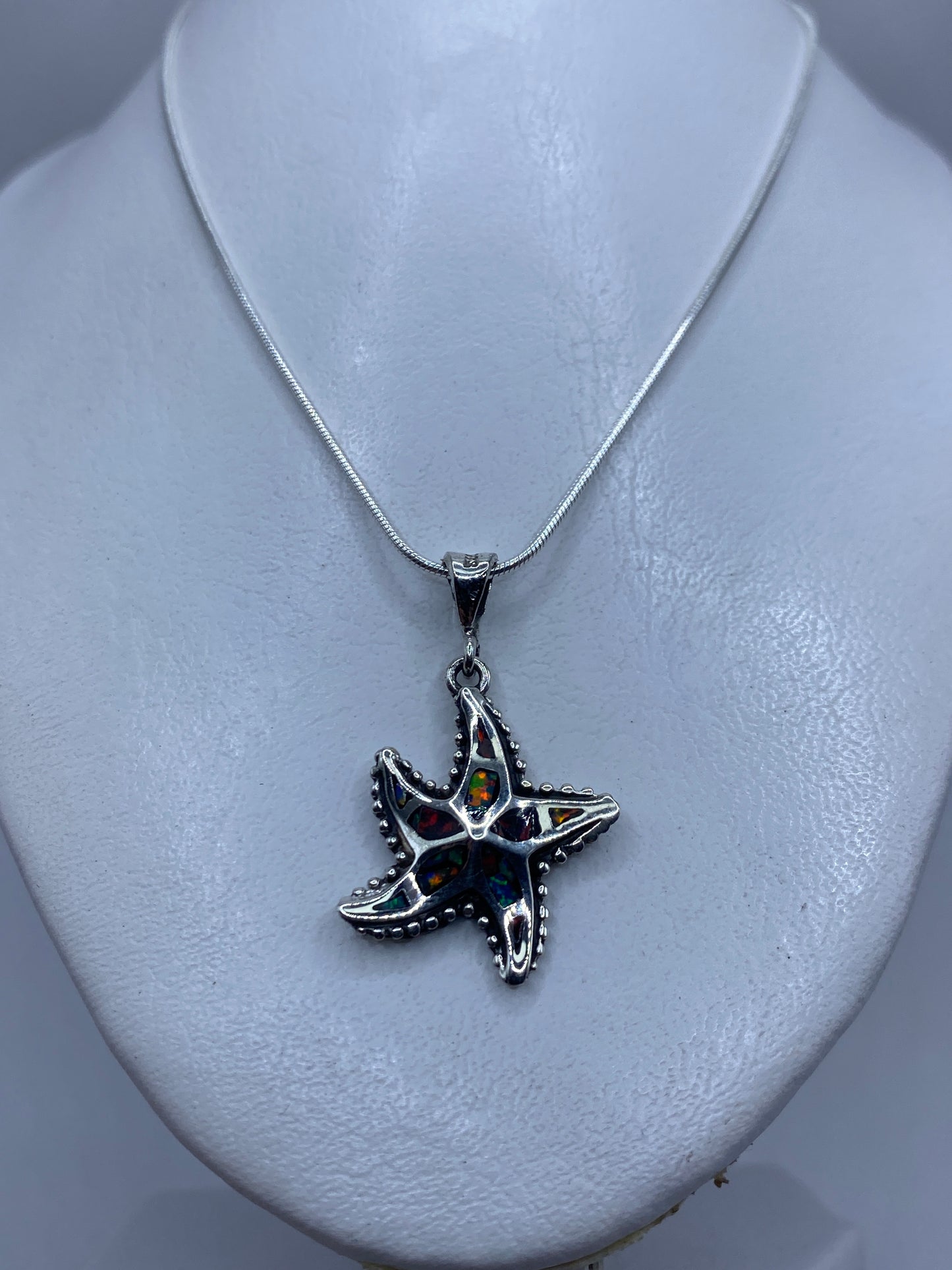 Estrella de mar granulada de plata .950 sobre cuello blanco, tamaño real de 4 centímetros