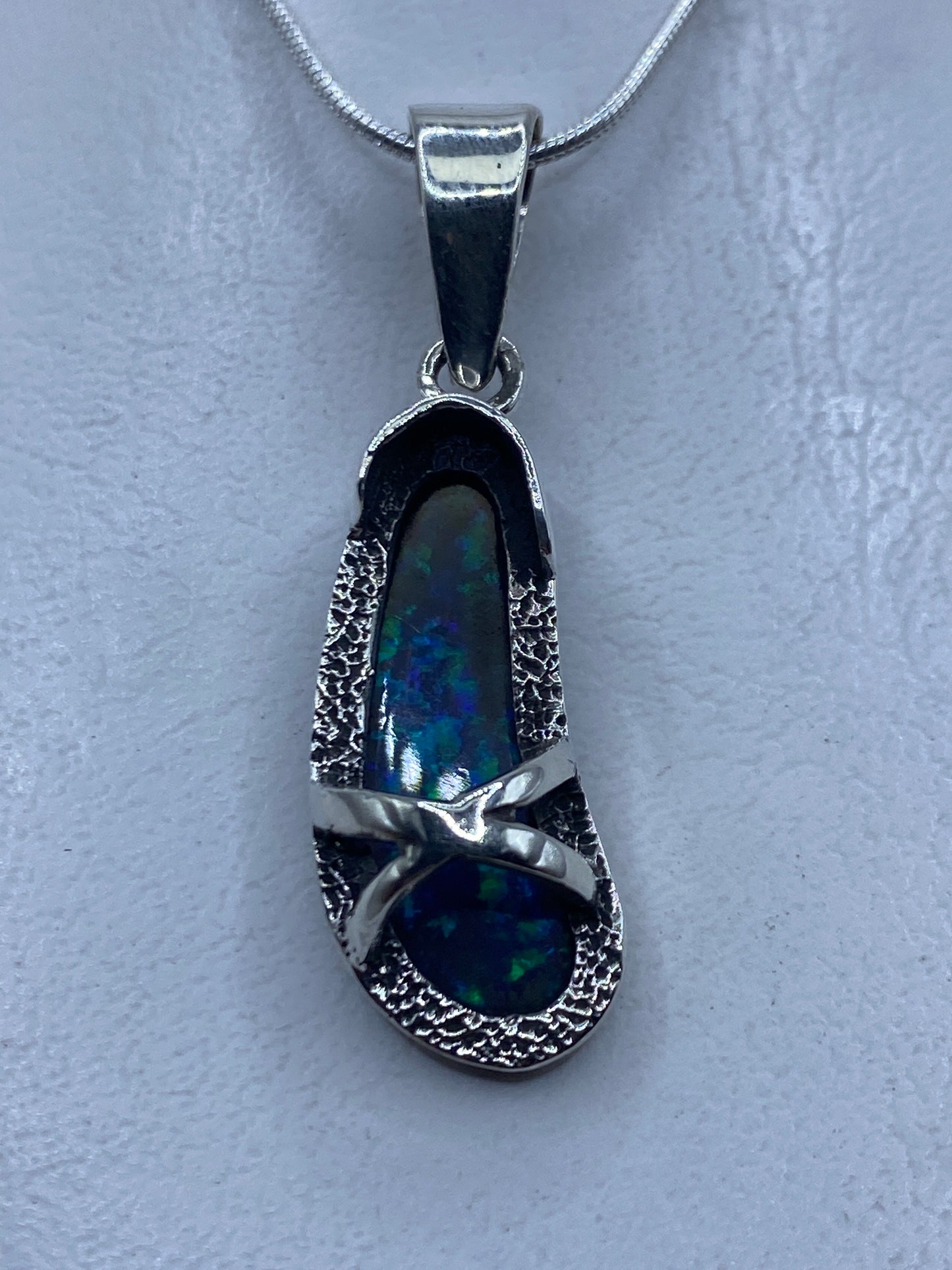 Dije de plata con ópalo de fuego azul colgando de una cadena de plata, vista frontal