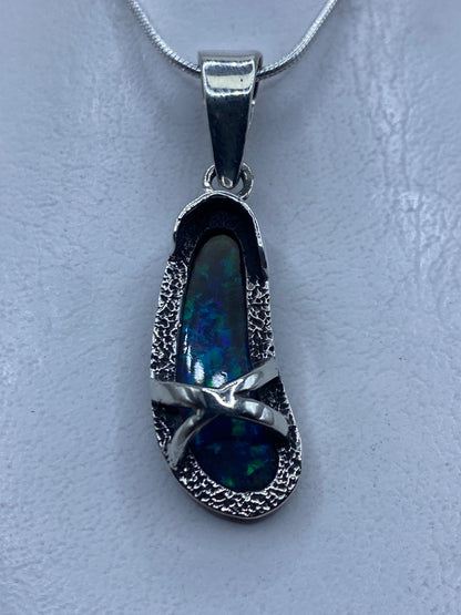 Dije de plata con ópalo de fuego azul colgando de una cadena de plata, vista frontal